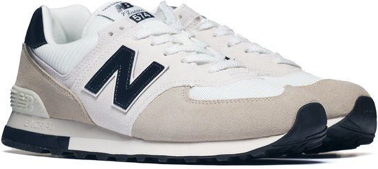 New Balance 574 sneakers, lichtgrijs suède met witte mesh en donkerblauwe N-logo's.