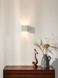 Witte vierkante wandlamp met dimbare LED, straalt licht naar boven en beneden op een witte muur.
