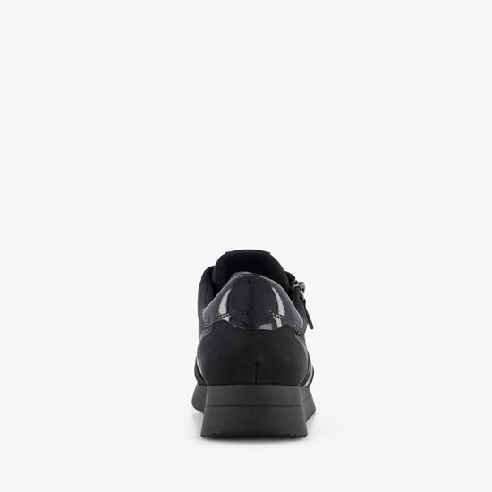 Achterkant van een zwarte sneaker met glanzende details en ritssluiting.