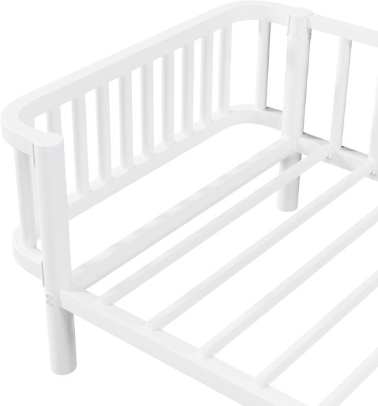 Detail van de hoek van een wit metalen dagbedframe met ronde spijlen.