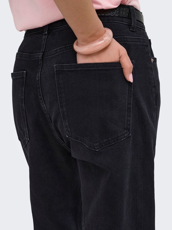 Close-up van de achterzak van een zwarte jeans, gedragen met een roze armband.