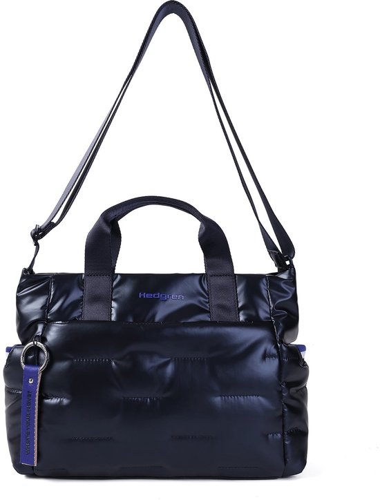 Donkerblauwe gewatteerde Hedgren tas met schouderband, hengsels en paars label met 'WHAT'S YOUR MOVE?'.