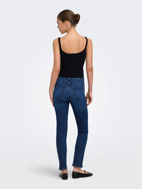 Model van achterkant gezien, draagt een zwarte top en donkerblauwe slim fit jeans.