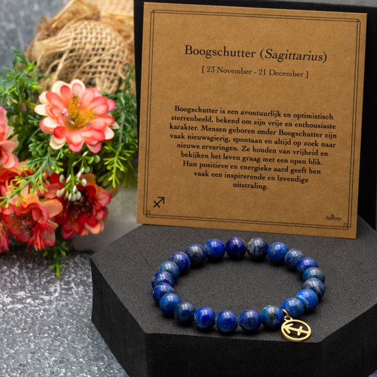 Lapis lazuli edelsteen armband met gouden Sagittarius bedel, naast een kaart met astrologische informatie.