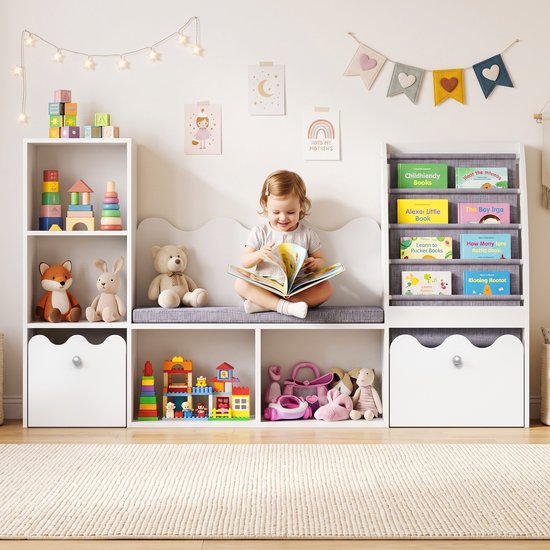 Wit opbergmeubel voor kinderen met een zittend kind dat leest; bevat planken, vakken en stoffen boekenorganizer.
