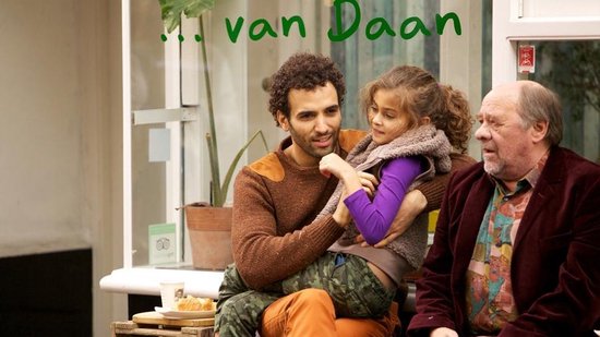 Man met krullend haar met een meisje op schoot, naast een oudere man.