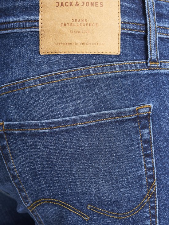 Achterkant van blauwe jeans met een bruin leren Jack & Jones label.