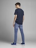 Man in een donkerblauw t-shirt en lichtblauwe jeans. Achteraanzicht.