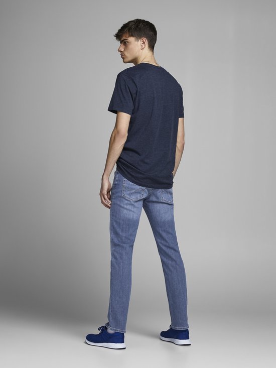 Man in een donkerblauw t-shirt en lichtblauwe jeans. Achteraanzicht.