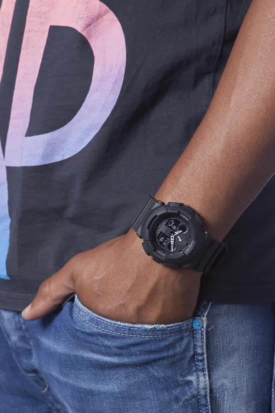 Zwarte G-Shock horloge om de pols van een man, met een detail van een t-shirt en jeans.
