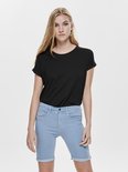 Vrouw draagt een zwarte top met opgerolde korte mouwen en lichtblauwe denim shorts.