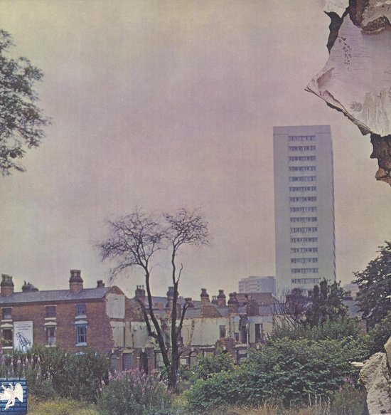 Achterkant van Led Zeppelin IV hoes met stadsgezicht en hoogbouw, met scheuren in de muur.
