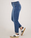Dichtbij opname van blauwe denim jeans met rechte pijp en omgeslagen zoom, met witte sneakers.