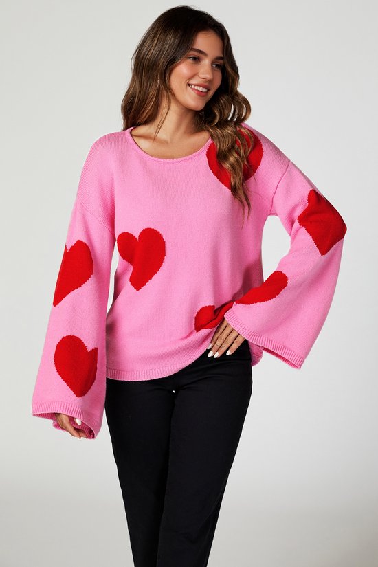 Model draagt een roze trui met wijde mouwen en rode hartjesprint.