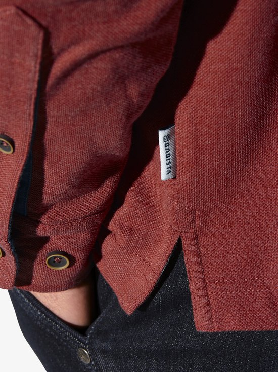 Detail van rood langarm polo shirt, zijkant met label 'BABISTA'.