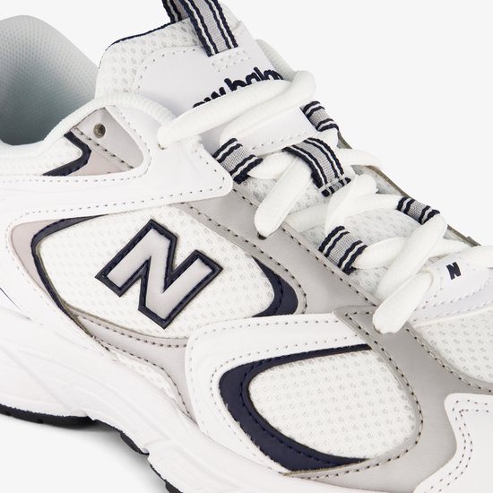 Close-up van de witte New Balance 408 sneaker, met het 'N' logo en witte veters.