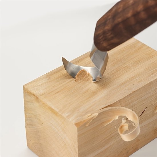 Een gebogen houtsnijmes wordt gebruikt om krullen van een houten blok te schrapen.