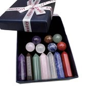 Een open blauwe geschenkdoos met een witte strik, gevuld met zeven gepunte edelstenen (paars, grijs, groen, roze, wit, blauw, rood) en zeven ronde edelstenen (paars, roze, blauw, groen, bruin, rood, wit).