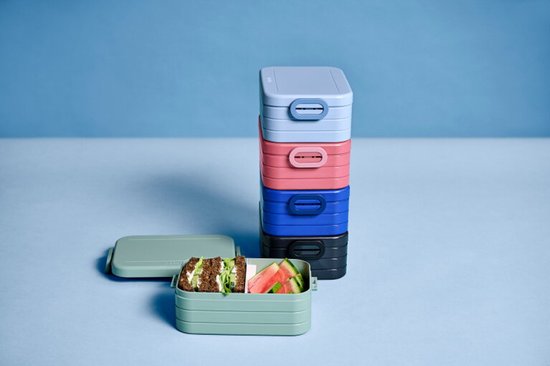 Pile de boîtes à lunch Mepal de différentes couleurs: gris clair, bleu clair, rose, bleu et noir. Boîte à lunch verte ouverte avec pain et pastèque.