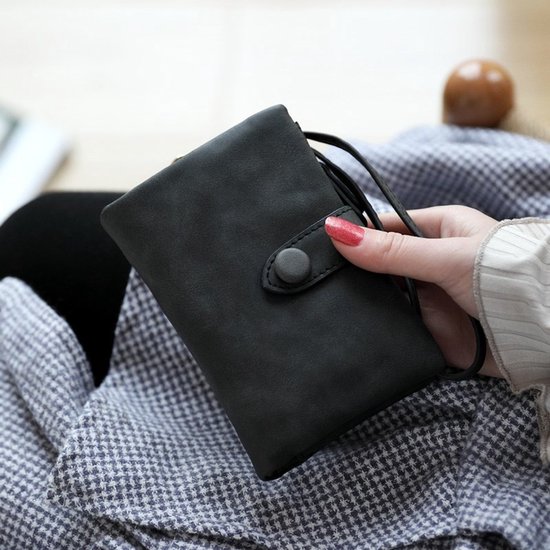 Een vrouw met rode nagellak houdt een gesloten zwarte portemonnee met drukknoop vast.
