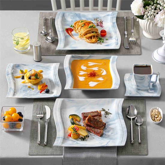 Gedekte tafel met marmerblauwe borden voor een diner. Borden met steak, spaghetti, dessert, soep en koffie.