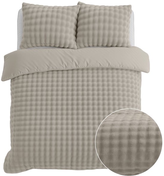Beige dekbedovertrek en kussenslopen met een ruitpatroon van pompons.
