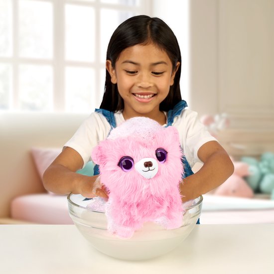 Meisje wast een roze pluizige puppy in een glazen kom met zeepsop.