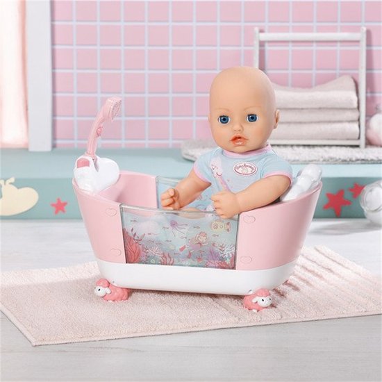 Baby pop in een roze badje met witte schaapjesvoetjes. De douchekop is roze en de badrand is versierd met zeedieren.