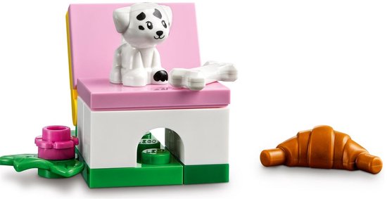 Een LEGO Friends hondje zit op een roze stoel met een bot. Een croissant ligt ernaast.