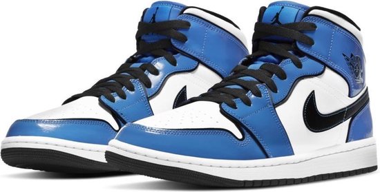 Gezamenlijke vooraanzicht van een paar blauw-witte Air Jordan 1 Mid SE sneakers met zwarte veters.