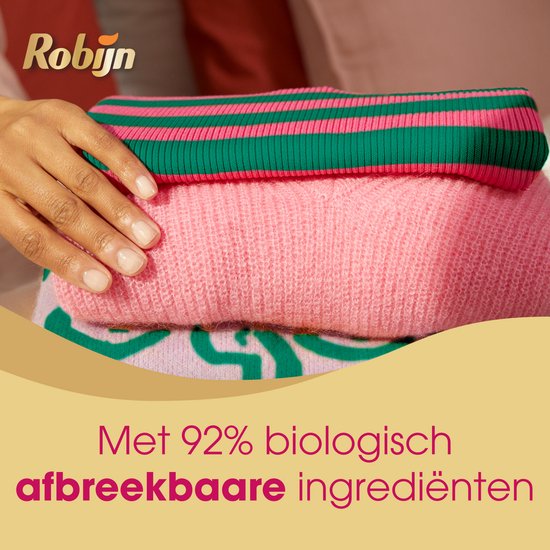 Pile de vêtements en tricot : un pull rose, un pull rose à rayures vertes. Une main repose sur le pull supérieur.