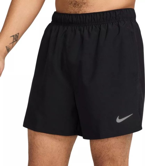 Zij-aanzicht van een man met zwarte Nike Challenger 5 inch shorts. De shorts hebben een elastische tailleband en een reflecterende Nike 'swoosh' logo.