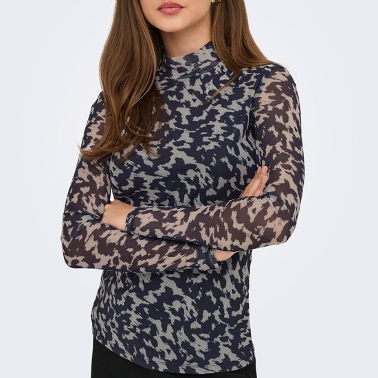 Model draagt longsleeve met hoge hals, abstracte print in nachtblauw en beige, armen gekruist.