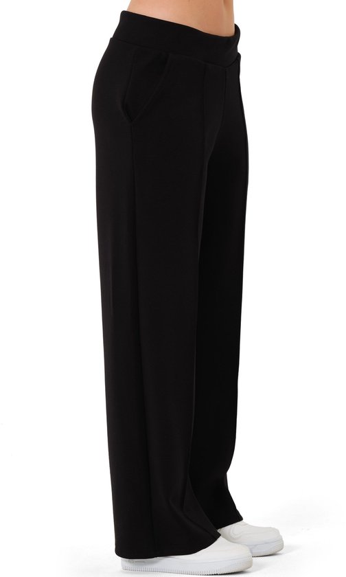 Zijzicht van zwarte wijde broek met rechte pijpen en witte sneakers.