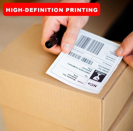 Een hand met een zwarte pen schrijft op een kartonnen doos, met een verzendlabel met de tekst 'HIGH-DEFINITION PRINTING' in rode letters.