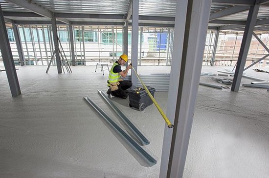Bouwvakker meet een constructie met gele Stanley rolbandmaat.