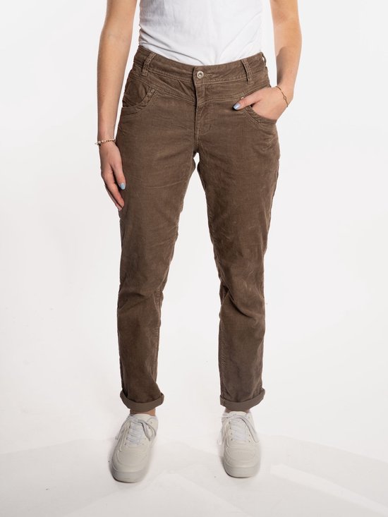 Bruine corduroy broek met opgerolde broekspijpen, gedragen door een model met witte sneakers.