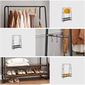 Zwart kledingrek met 2 houten planken, kledinghangers, schoenen, tas, doos en kussens.