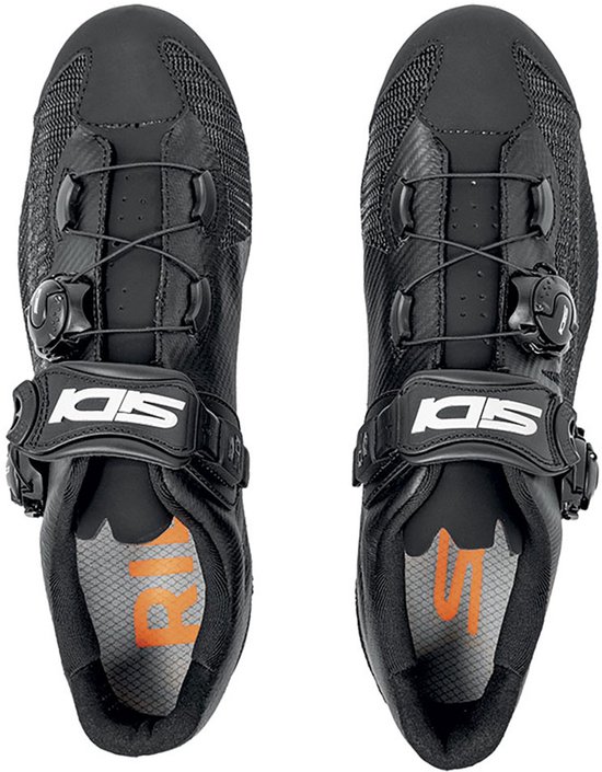 Bovenkant van zwarte Sidi racefietsschoenen met veters, klittenband en dubbele draaisluiting. Oranje binnenzool met Sidi-logo.