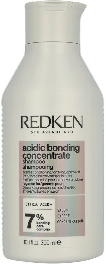 Flacon de shampoing blanc Redken avec étiquette rose indiquant 'acidic bonding concentrate shampoo'.