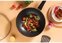 Wok noir antiadhésif rempli de crevettes, de légumes et de citron.