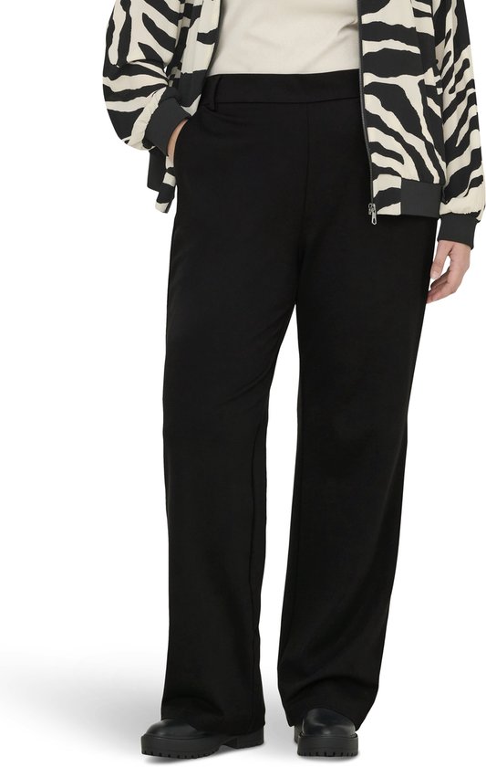 Een model draagt een beige top, een jasje met zebraprint en een zwarte wijde broek.