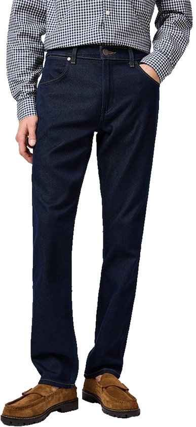 Man in donkerblauwe jeans met regular fit, bruine loafers en geruit overhemd.