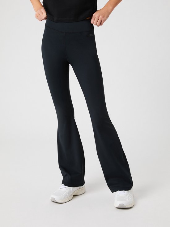 Meisje in zwarte flare sportbroek met "BORG" logo op de heup en witte sneakers.