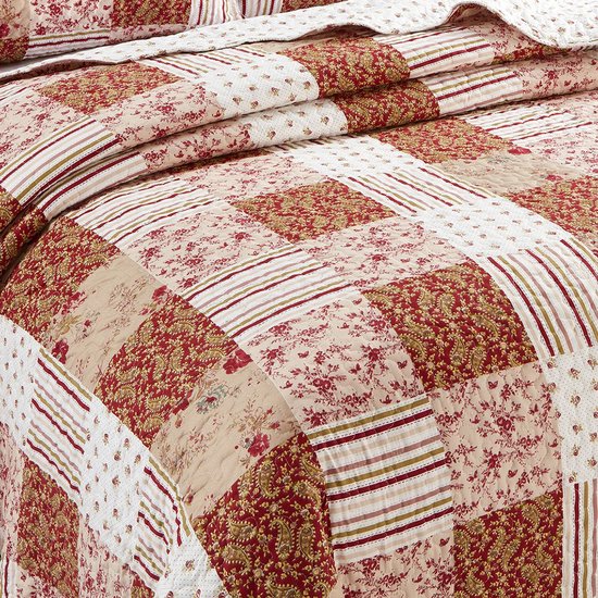 Gedetailleerd zicht op de bordeauxrode patchwork quilt. Bloemen-, paisley- en streepmotieven op beige.