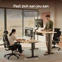 Man en vrouw gebruiken een verstelbaar bureau. 'Past zich aan jou aan', '15% meer bereik dan concurrenten', 'Max: 122 cm', 'Min: 72 cm'.