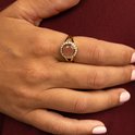 Gouden ring met een ronde, lichtroze gespikkeld steentje, omringd door zirkonia's.