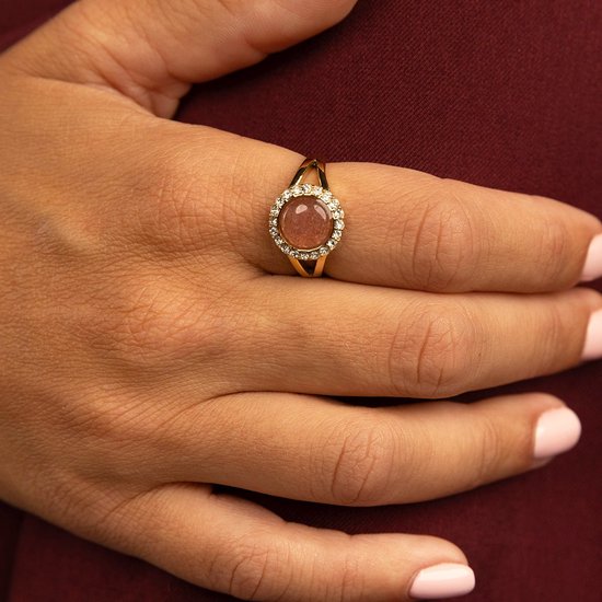 Gouden ring met een ronde, lichtroze gespikkeld steentje, omringd door zirkonia's.