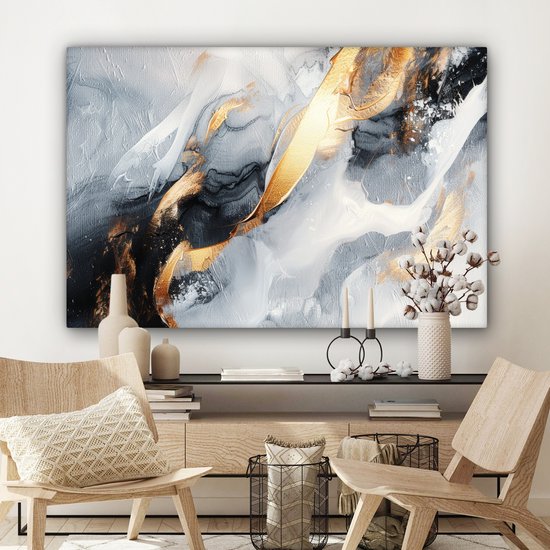 Peinture abstraite avec des touches de peinture dorée, noire et blanche, suspendue au-dessus d'un meuble en bois avec des chaises en bois.
