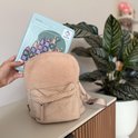 Een hand houdt de pastelkleurige LearnetiQ reisset boven een teddy rugzak.
